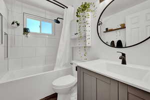 Full bathroom featuring wood-type flooring, vanity, toilet, and shower / bath combination with curtain