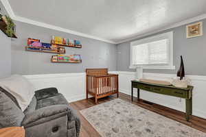 Living area with a textured ceiling, wood-type flooring, and crown molding