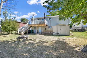 Back of house with a lawn, a deck, a shed, and a fire pit