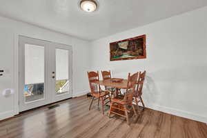 Dining room featuring french doors, a textured ceiling, and hardwood / wood-style floors