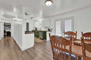 Dining area with light hardwood / wood-style flooring, a textured ceiling, french doors, and sink