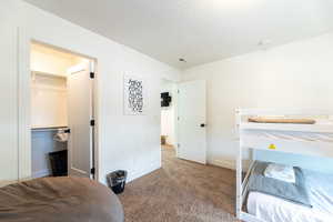 Bedroom featuring a closet, carpet, a textured ceiling, and a walk in closet