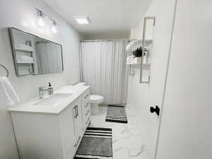 Bathroom with a textured ceiling, vanity, and toilet