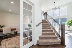 Staircase featuring wood-type flooring, ceiling fan, and french doors