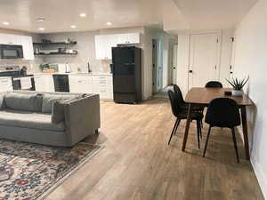 Kitchen featuring black appliances, tasteful backsplash, and white cabinets