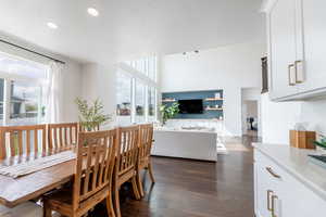 Dining room featuring a textured ceiling, a towering ceiling, and dark wood-type flooring