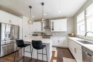 Kitchen with sink, white cabinetry, wall chimney range hood, appliances with stainless steel finishes, and dark hardwood / wood-style flooring