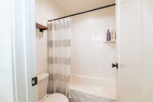 Bathroom with toilet and shower / tub combo with curtain