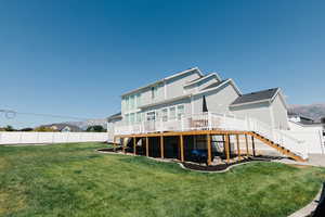 Rear view of house with a wooden deck and a yard