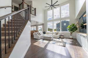 Living room with a high ceiling, dark hardwood / wood-style flooring, and ceiling fan