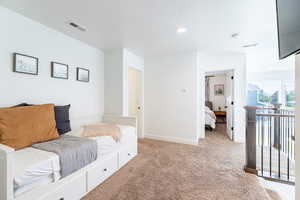 Bedroom with a textured ceiling and light colored carpet