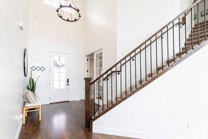 Foyer entrance with a notable chandelier, dark hardwood / wood-style floors, and a high ceiling