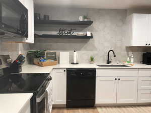 Kitchen with white cabinets, sink, decorative backsplash, and black appliances