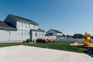 Rear view of property with a playground, a wooden deck, a yard, and a patio