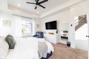 Bedroom featuring a tray ceiling, ceiling fan, and light colored carpet