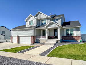 Craftsman-style house featuring a garage, a front lawn, and covered porch