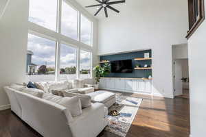 Living room featuring ceiling fan, a towering ceiling, and dark hardwood / wood-style floors