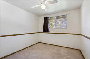 Carpeted empty room featuring ceiling fan and a textured ceiling