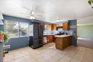 Kitchen with ceiling fan, appliances with stainless steel finishes, kitchen peninsula, and a healthy amount of sunlight