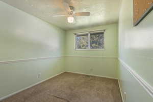 Carpeted empty room featuring a textured ceiling and ceiling fan