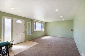 Carpeted foyer entrance with a textured ceiling