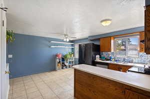 Kitchen with a textured ceiling, sink, backsplash, appliances with stainless steel finishes, and ceiling fan