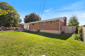 Rear view of property featuring a lawn, a shed, and central AC unit