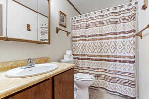 Bathroom featuring a textured ceiling, vanity, toilet, and a shower with shower curtain