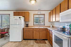 Kitchen featuring a textured ceiling, light hardwood / wood-style flooring, sink, and white appliances