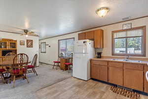 Kitchen featuring a wealth of natural light, a textured ceiling, white fridge, and sink