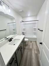 Full bathroom featuring a textured ceiling, tub / shower combination, vanity, and toilet