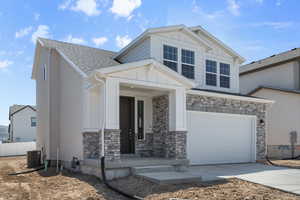 View of front of home with a garage and central AC