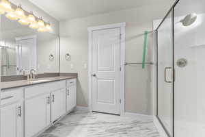 Bathroom featuring a shower with shower door and vanity