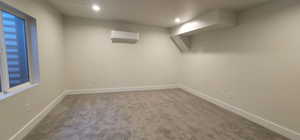 Carpeted empty room featuring a wall unit AC