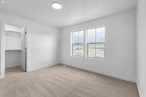 Unfurnished bedroom with light carpet, a closet, and a walk in closet