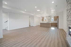 Unfurnished living room with light wood-type flooring, a fireplace, and sink