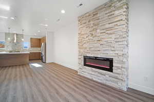 Unfurnished living room with light wood-type flooring, a fireplace, and sink