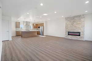 Unfurnished living room with a stone fireplace and light hardwood / wood-style flooring