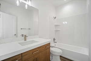 Full bathroom featuring washtub / shower combination, hardwood / wood-style floors, vanity, and toilet