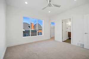 Unfurnished bedroom with light colored carpet, ceiling fan, a walk in closet, and a closet