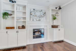 Unfurnished living room with ornamental molding, a fireplace, and dark hardwood / wood-style flooring