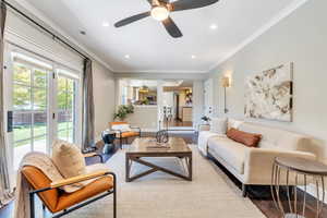 Living room featuring wood-type flooring, ornamental molding, and ceiling fan