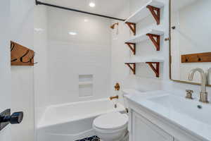 Full bathroom with vanity, tiled shower / bath combo, and toilet