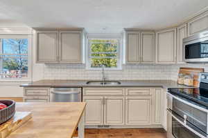 Kitchen featuring backsplash, stainless steel appliances, cream cabinets, hardwood / wood-style floors, and sink