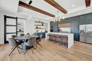 Dining room featuring light hardwood / wood-style flooring, beam ceiling, and a barn door