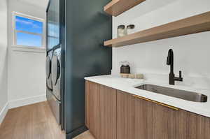 Laundry area with light hardwood / wood-style floors and sink