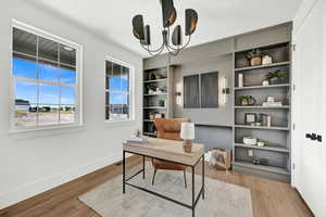 Home office with light wood-type flooring and a chandelier