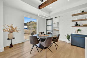 Dining area with a barn door, beam ceiling, and light wood-type flooring