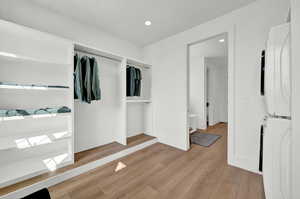 Walk in closet featuring light wood-type flooring and stacked washing maching and dryer