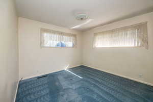 Unfurnished room featuring crown molding and dark colored carpet